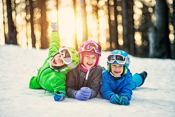 happy little skiers lying on ski slope - pre adolescent child child group of people little boys imagens e fotografias de stock