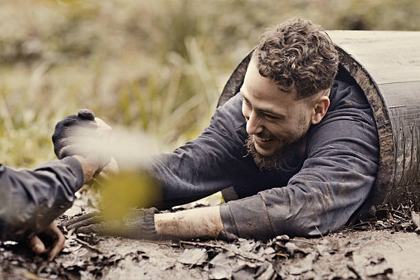 istock Caucasian young man being helped from tunnel during obstacle course 624874730
