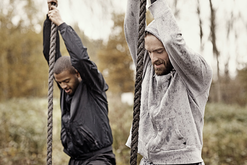 Two Mud Run teammates climbing ropes during an obstacle course