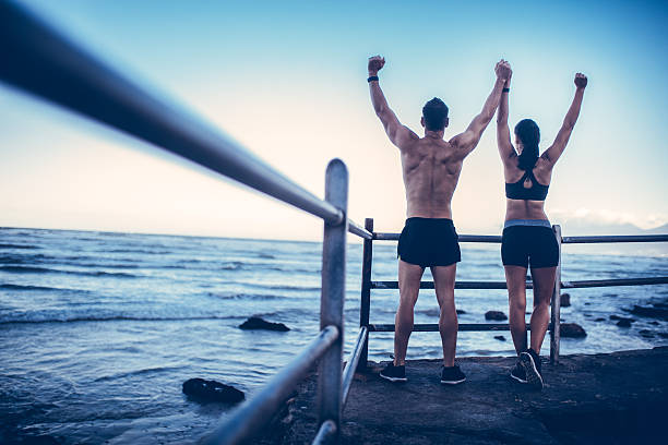 Young adult caucasian couple doing conquer pose after run