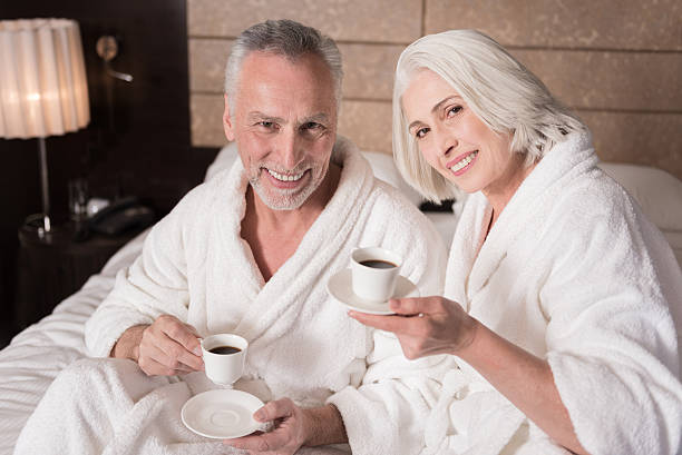 istock Happy pleasant aged couple drinking coffee on the bed 624875542