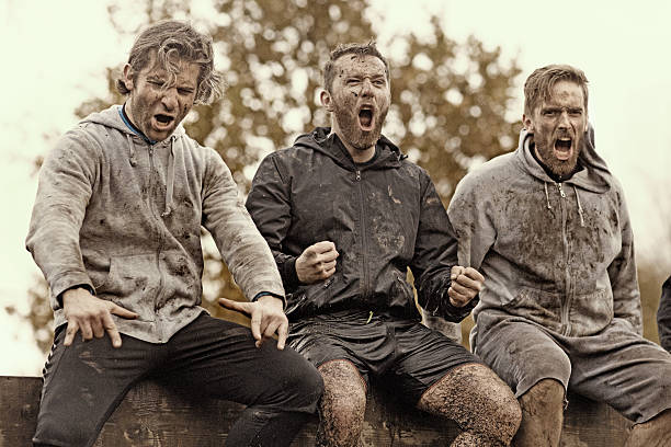 istock Multiethnic mud run team of men sitting shouting obstacle course 624875790