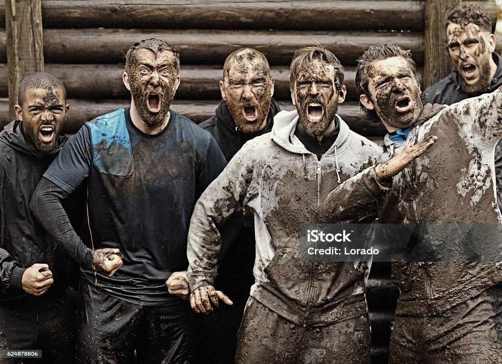 Multiethnic mud run team of men yelling during obstacle course Men Stock Photo