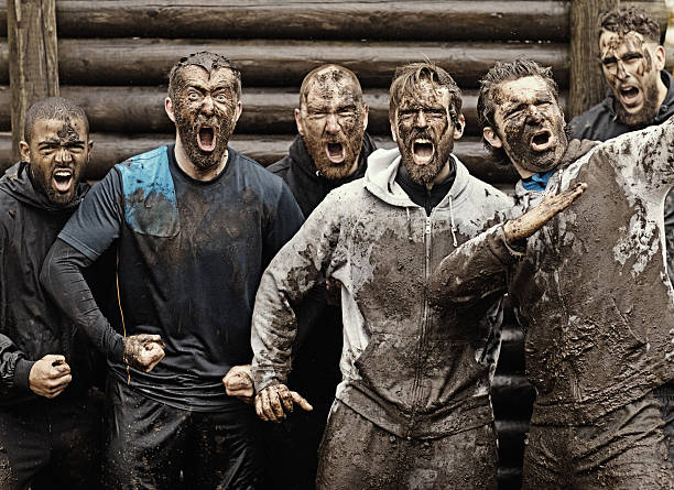 Multiethnic mud run team of men yelling during obstacle course Multiethnic mud run team of men yelling during obstacle course macho photos stock pictures, royalty-free photos & images