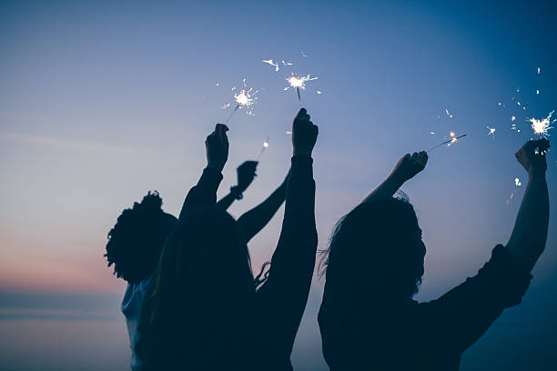 freunde feiern party mit sekt und feuerwerk bei sonnenuntergang - wunderkerze stock-fotos und bilder