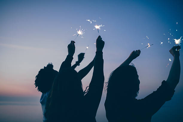 Friends celebrate party with sparklers and firework at sunset Friends celebrate new year's eve party with sparklers and firework at sunset new years eve parties stock pictures, royalty-free photos & images