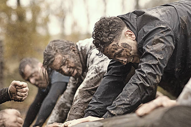 istock Multiethnic mud run team of men climbing along obstacle course 624879328