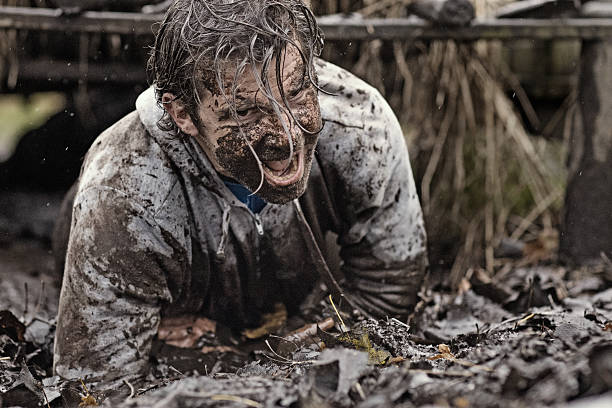 istock Caucasian brunette handsome man crawling under obstacle during mud run 624879618