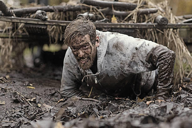 Caucasian blonde handsome man crawling under obstacle during mud run