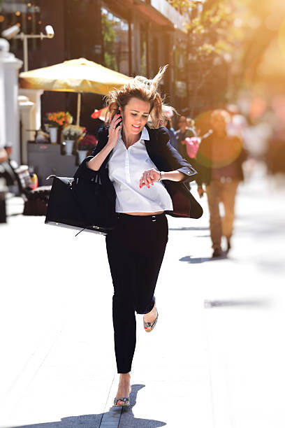 Business woman rushing to work Beautiful business woman talking on the phone and rushing to work on the street. time pressure stock pictures, royalty-free photos & images