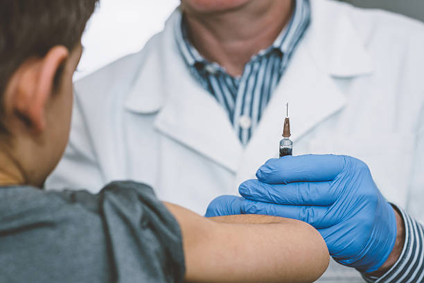 Doctor holding a vaccine syringe. Little boy ready. Doctor holding a vaccine syringe. Little boy ready to get a shot polio vaccine stock pictures, royalty-free photos & images