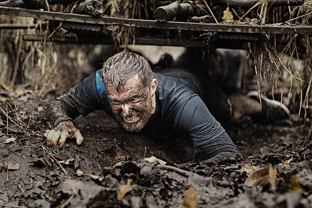 istock Caucasian blonde handsome man crawling under obstacle during mud run 624879980
