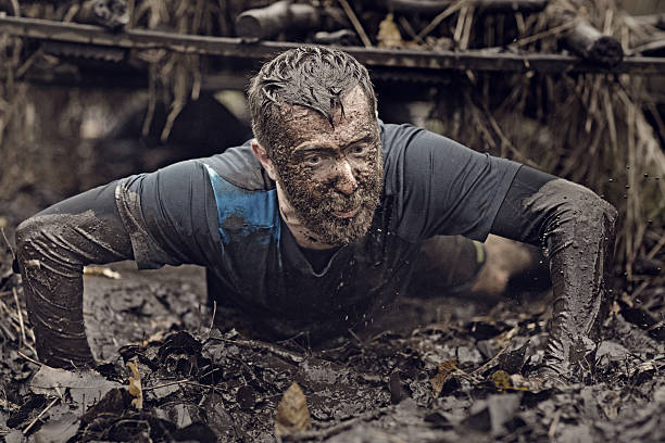 istock Caucasian blonde handsome man crawling under obstacle during mud run 624880002