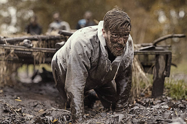 istock Caucasian blonde handsome man crawling under obstacle during mud run 624880026
