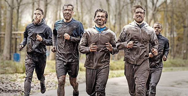 istock Multiethnic mud run team of men running during obstacle course 624880150