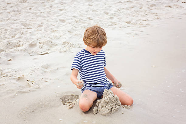 istock Little kid boy having fun with building sand castles 624886136