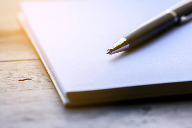 istock Pen on Notebook On Wood Background with Sun Light 624893130