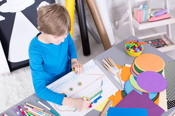 istock Boy having fun with paper and colored pencils 624896744