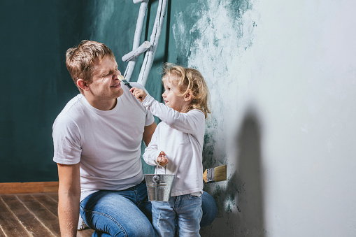 Family, happy daughter with dad doing home repair, paint walls, together with love