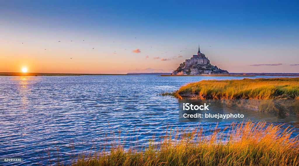 Le Mont Saint-Michel at sunset, Normandy, France Panoramic view of famous Le Mont Saint Michel tidal island in beautiful golden evening light at sunset in summer, Normandy, France. Mont Saint-Michel Stock Photo