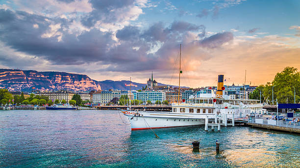 Historic city of Geneva with paddle steamer at sunset, Switzerland Panoramic view of the historic city center of Geneva with traditional paddle steamer boat on Lake Geneva in beautiful golden evening light at sunset with blue sky and clouds in summer, Switzerland. geneva switzerland photos stock pictures, royalty-free photos & images