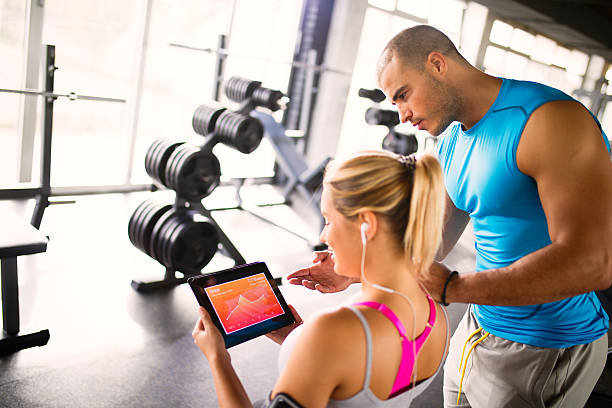 istock Young woman discussing workout progress with fitness instructor 624912322