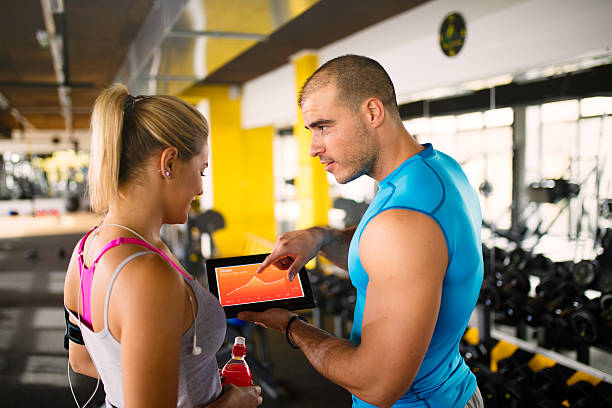 istock Young woman discussing workout progress with fitness instructor 624912552