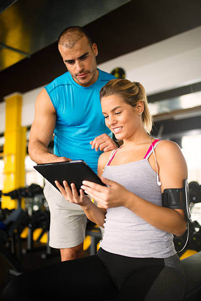 istock Young woman discussing workout progress with fitness instructor 624912652