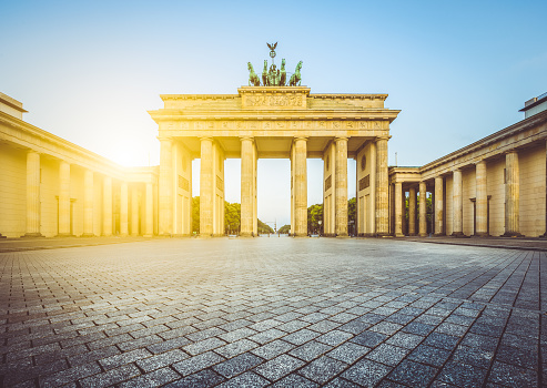 Famous Brandenburger Tor (Brandenburg Gate), one of the best-known landmarks and national symbols of Germany, in beautiful golden morning light at sunrise with lens flare effect, Berlin, Germany