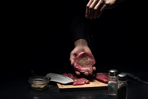 Flavored one. Close up of mans hands spicing the meat while cooking and working as a chef in restaurant.