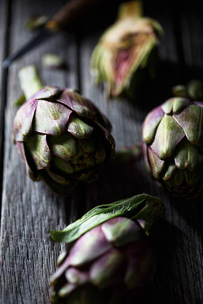 Artichoke Purple and green artichoke on wood background Artichoke stock pictures, royalty-free photos & images