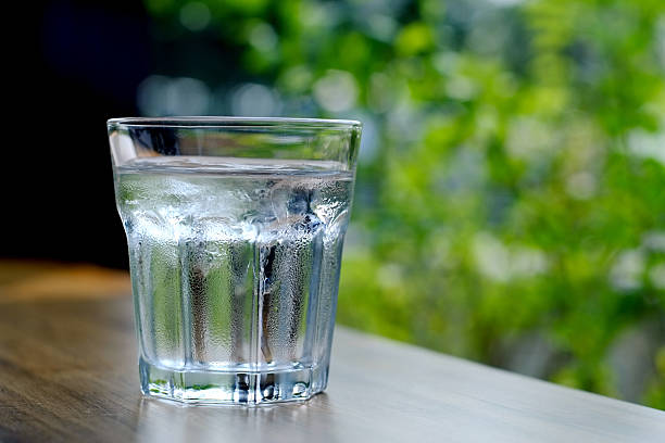 istock Glass of cold water with green leaves in background 624924862