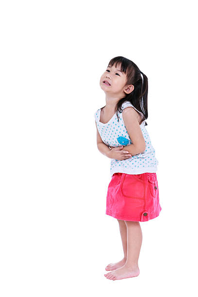Asian child in pink skirt suffering from stomachache. Isolated o stock photo