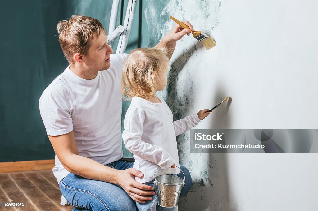 Familia, hija feliz con papá haciendo reparación del hogar, paredes de pintura, - Foto de stock de Pintar libre de derechos