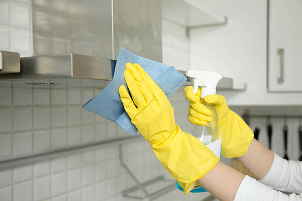 Closeup of female hands in gloves cleaning the extractor hood Close up of female hands in rubber protective yellow gloves cleaning the kitchen metal extractor hood with rag and spray bottle detergent. Home, housekeeping concept cleaning stove domestic kitchen human hand stock pictures, royalty-free photos & images