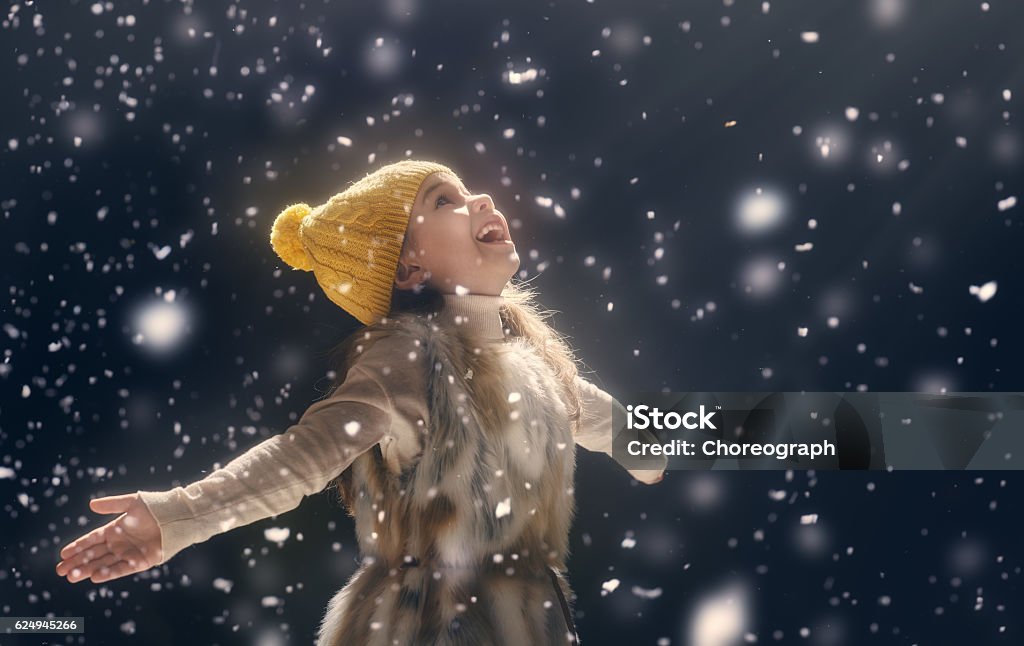 kid on dark background Happy child girl playing on a snowy winter walk. Little girl enjoys the game. Child girl playing outdoors in snow. Outdoor fun for winter vacation. Portrait kid on dark background. Child Stock Photo