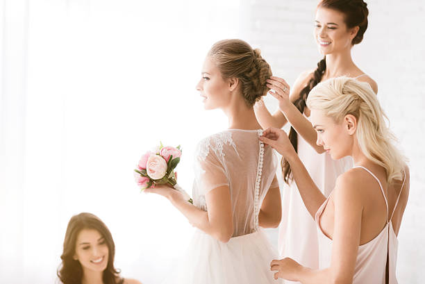 istock Delighted bridesmaids helping the bride to get ready 624945550