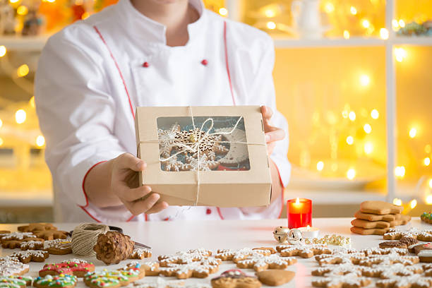 Hands of confectioner showing a box with gingerbread cookies