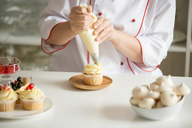 istock Close up of hands topping a cupcake with cream 624947116