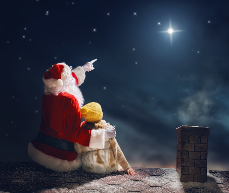 niña y Santa Claus sentados en el techo photo