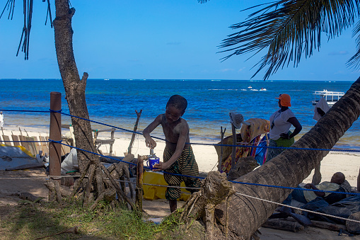 bamburi beach, kenya - November 15, 2016: local people walking on Sarova beach, south of Mombasa. child drink water from fountain Kenya beaches attract a lot of tourists from all over the world.