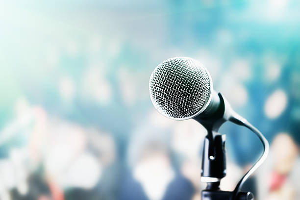 Microphone and defocused audience waiting for the show to begin A vocal microphone in close up in front of a defocused audience in theatre seating, waiting for the performance to start. microphone stand photos stock pictures, royalty-free photos & images