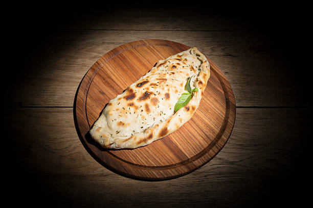 Fried thick cheburek served on a wood tray on old wooden table in dark