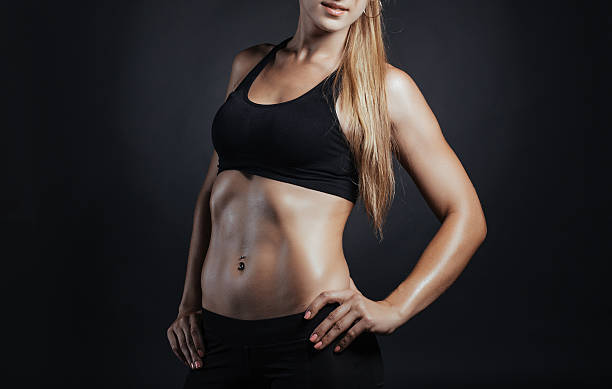 Muscular fitness woman posing on a dark background in studio stock photo
