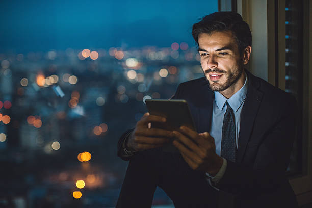 businessman holding a tablet at night - ceo financial advisor businessman serious imagens e fotografias de stock