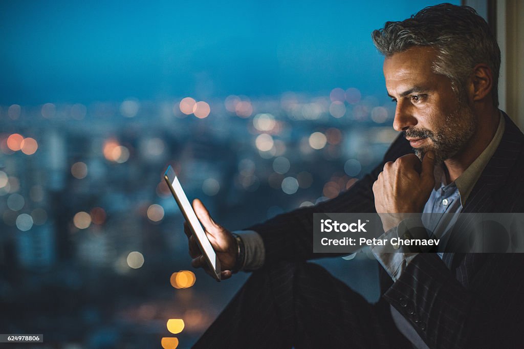 Geschäftsmann schaut nachts auf digitales Tablet - Lizenzfrei Finanzen Stock-Foto
