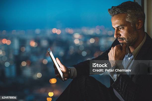 Geschäftsmann Schaut Nachts Auf Digitales Tablet Stockfoto und mehr Bilder von Finanzen - Finanzen, Geschäftsleben, Technologie