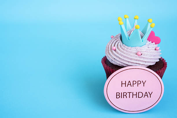Happy birthday cupcake with crown and pink heart over blue background with copy space, Gift for birthday