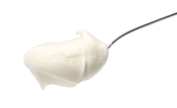 Sour cream in spoon isolated on white background