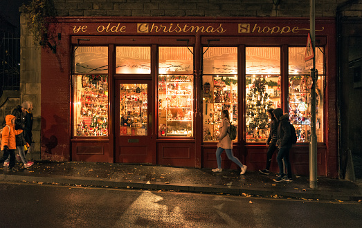 Edinburgh, UK - November 21, 2016: People on the pavement passing Ye Olde Christmas Shoppe, a traditional gift shop on Canongate, part of the Royal Mile in the city's historic Old Town.